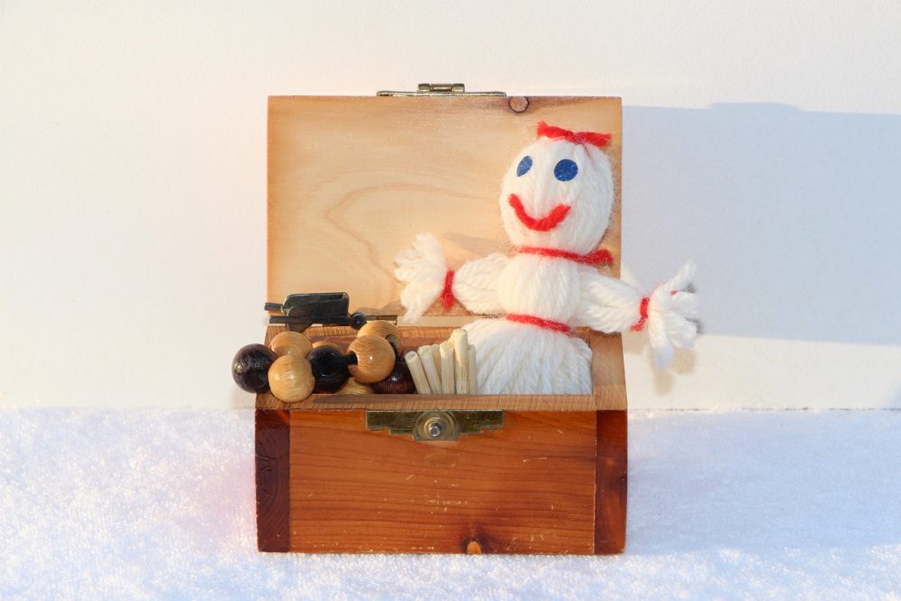 Coffre avec poupée de laine, boules de bois et autres petits jouets